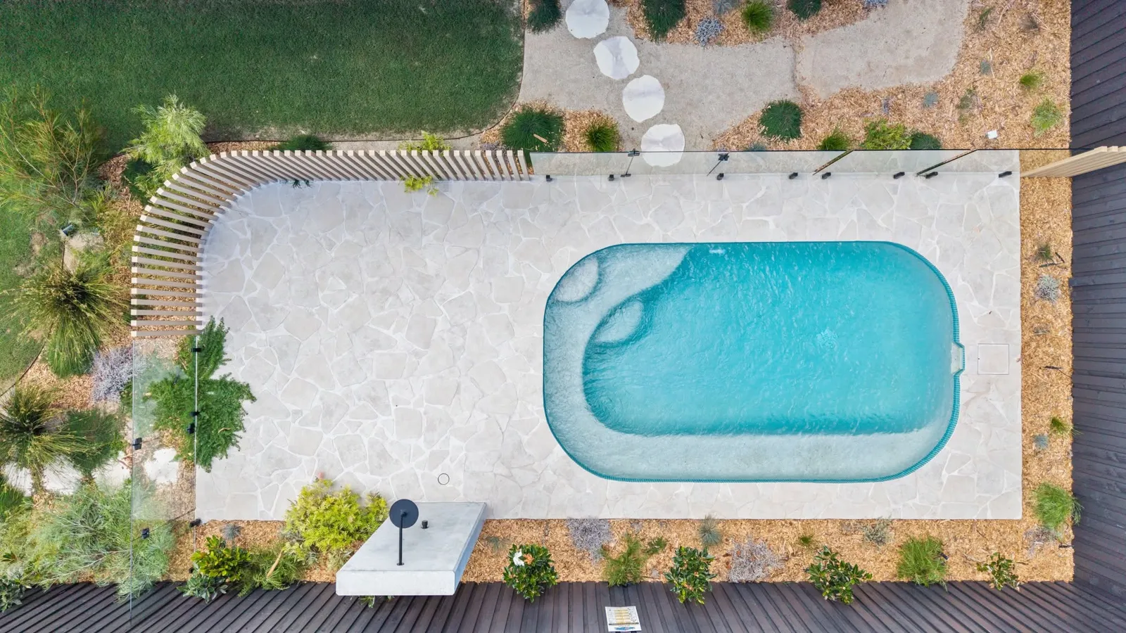 Aerial view of a Cairns pool surround with crazy paving, timber batten screen, glass fence and deck by MLS Projects