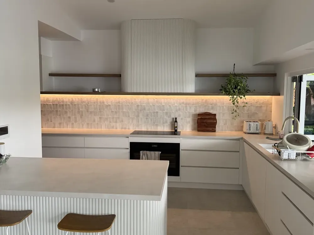 Renovated white kitchen with curved island bench and stone splashback, built by MLS Projects in Cairns